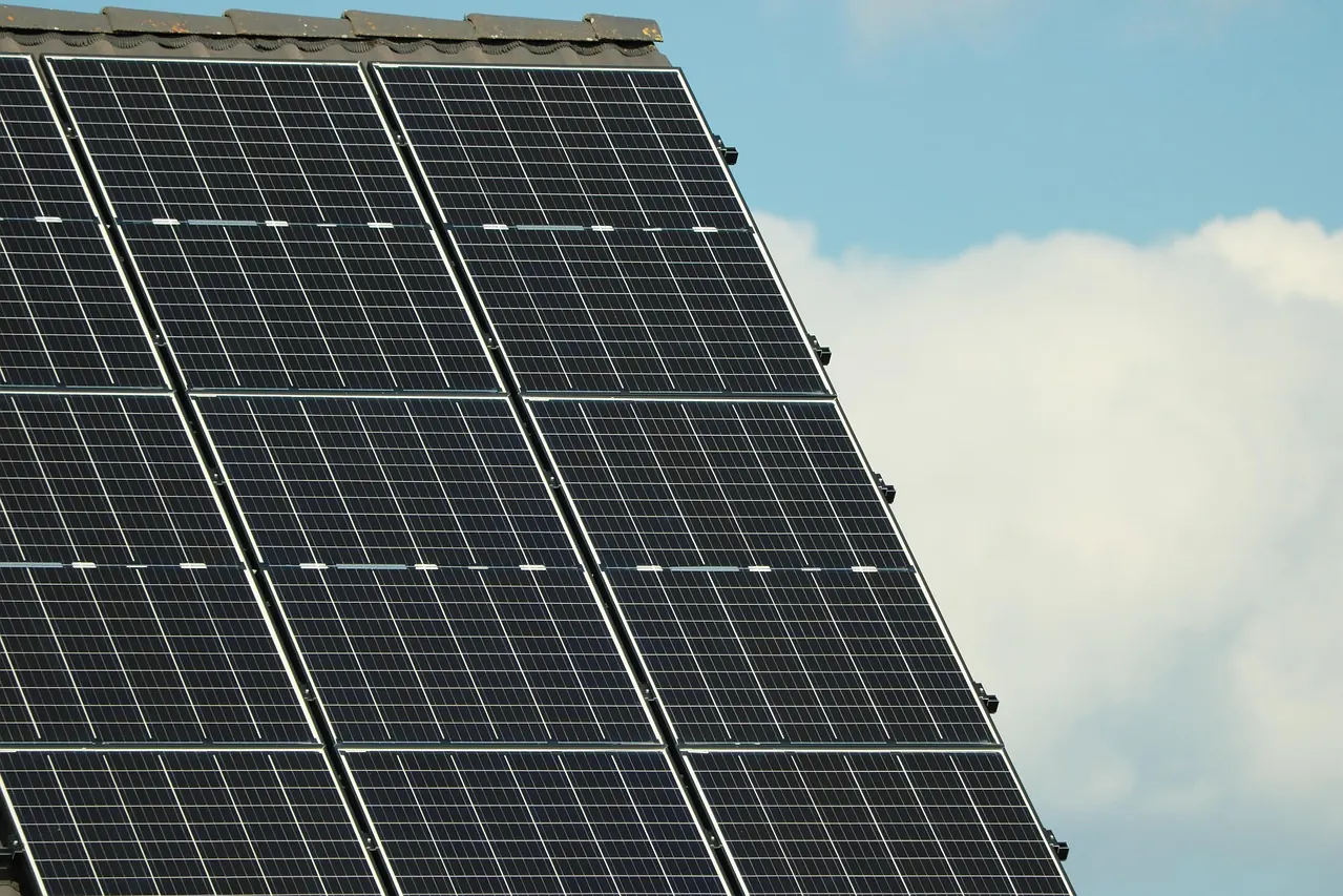 Schwarze Solarmodule in zwei Spalten auf einem steilen Dach vor weißen Wolken (Leun, Lahn-Dill-Kreis)