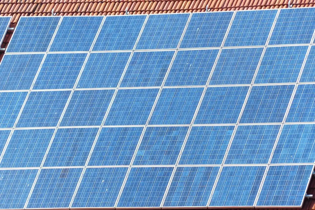 Nahaufnahme blauer polykristalliner Solarmodule auf einem roten Ziegeldach (Andechs, Landkreis Starnberg)