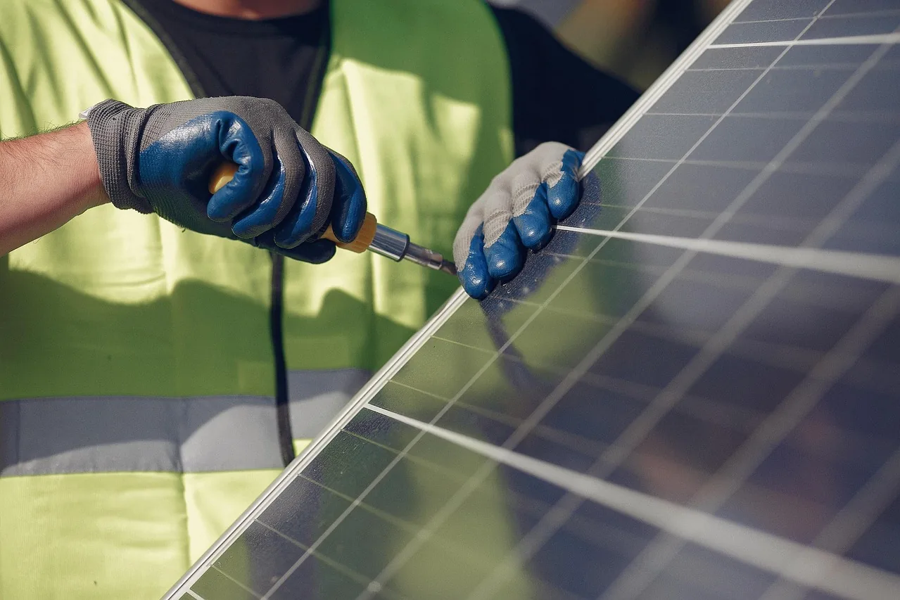 Monteur in Warnweste arbeitet mit Schraubendreher am Rahmen eines Solarmoduls (Goldberg, Ludwigslust-Parchim)