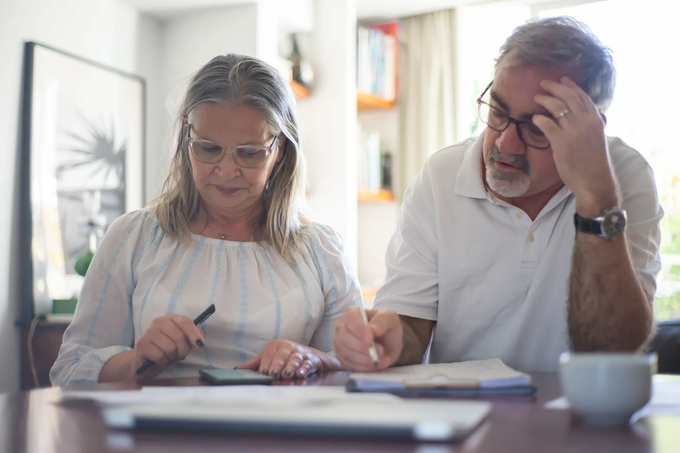 Älteres Paar prüft am Tisch Rechnungen und Unterlagen, der Mann wirkt nachdenklich (Oberteuringen, Bodenseekreis)